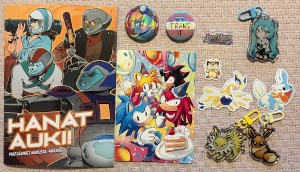 Biker Mice from Mars fanzine, Sonic the Hedgehog postcard, My Little Pony pin, transgender pin, he/they pin, Hatsune Miku charm, Pokémon stickers and charms